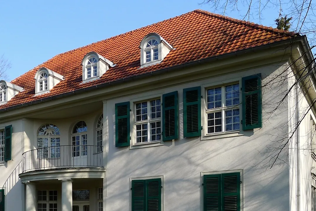 Dachpartie einer hellen Berliner Stadtvilla mit Gauben und grünen Fensterläden